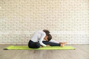 Latin woman practicing yoga on mat photo