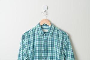 camisa colgante con colgador de madera en la pared foto