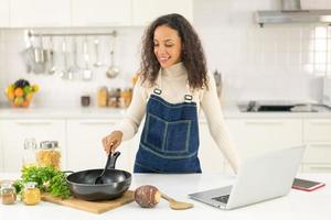 mujer latina grabando video y cocinando en la cocina foto