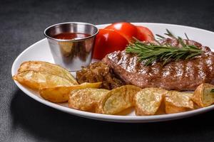 Delicious juicy beef steak with baked potatoes and sauces on a white dish photo