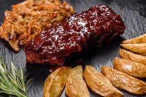 Spicy barbecued pork ribs served with BBQ sauce on chopping board photo