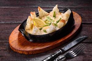 A delicious seafood dish baked with cheese and breadcrumbs in a cast iron bowl photo