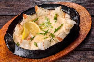 A delicious seafood dish baked with cheese and breadcrumbs in a cast iron bowl photo