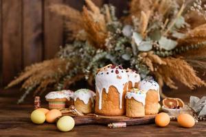 Easter holiday concept. Easter cakes , willow, painted eggs and candle on rustic wooden table photo