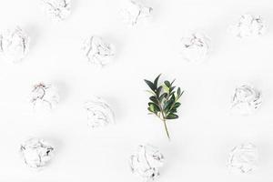 overhead shot of crumpled paper in oder and green twig among on white background. zero waste concept photo