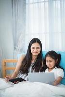 mother teaching child girl for doing homework at home, family education activity concept