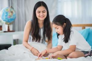 mother teaching child girl for doing homework at home, family education activity concept