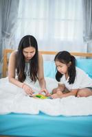 mother teaching child girl for doing homework at home, family education activity concept photo