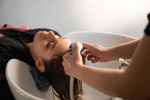 peluquera y hermosa mujer cliente haciendo tratamiento de salud del cabello en un salón de estilo de moda foto