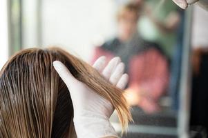 peluquera y hermosa mujer cliente haciendo tratamiento de salud del cabello en un salón de estilo de moda foto