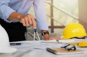 Engineers are planning a structure sketch with circular tools. Complete with architect equipment and architectural blueprints at the desk. photo