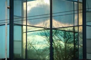 Beautiful reflection in glass window with sunset sky, tree branches and wires photo