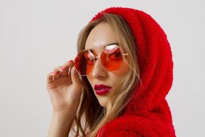 Closeup woman face in red sunglasses isolated on white background. Girl in red hoodie sweatshirt and red lips makeup. Fashion Beauty concept. Beautiful face skin and fashionable accessories concept. photo