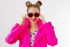 Happy, shock, excited woman face closeup. Girl in bright pink autumn clothes, red sunglasses isolated on white background, copy space. Beautiful female surprised, cheerful. Fun funny model screaming photo