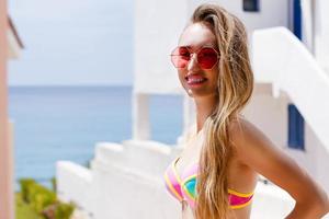 Close Up Of Happy Girl in pink sunglasses. Summer holidays and fun time weekend. Summertime concept. Smiling young woman in fashion swimsuit. Selective focus. Beach Summer outfit. Copy Space photo