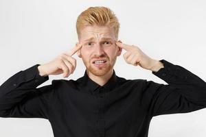 Young man headache. Redheaded guy with red beard in thinking process isolated. Close up of male face. Mental and mind working. Brain power and creating idea concept. Male in black shirt. Head pain photo