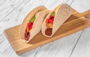 Taco with filling on the wooden background photo