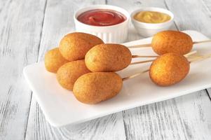 Corn dogs on white serving plate photo