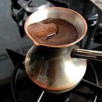 Barista preparing hot tasty drink from copper turk photo