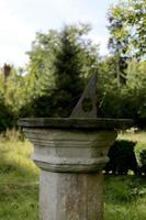 Very old sundial shows time in dense vegetation forest photo