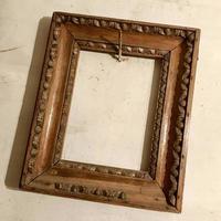 Old wooden empty photo frame hanging on the wall nailed rusty steel nail