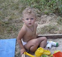 Hermoso bebé en el arenero infantil posando fotógrafo cerca del arenero foto