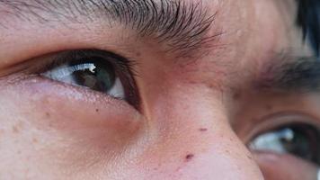 olhos de close-up do adolescente asiático, olhando para longe à luz do sol.