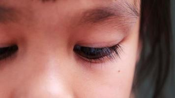 retrato de close-up de criança asiática lendo um livro dentro de casa. lindos olhos castanhos, cílios longos. video