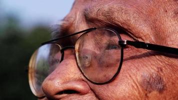 Close-up face of senior man in glasses looking out into the distance in the sunlight. vision and old people concept