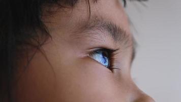 Close up portrait of little Asian child looking up into the sky. Beautiful brown eyes, long eyelashes.