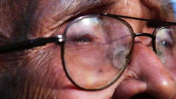 close-up gezicht van senior man met bril kijkt uit in de verte in het zonlicht. visie en oude mensen concept video