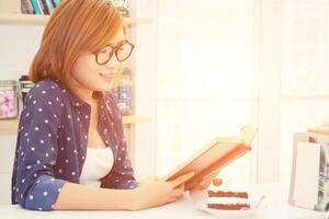 Charming young woman sitting reading book in the cafe photo