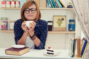 Una mujer joven y hermosa que sostenía una taza de café tenía un olor fragante en la cafetería foto