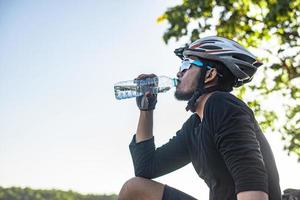 los ciclistas de montaña se paran en la cima de la montaña y beben una botella de agua. foto
