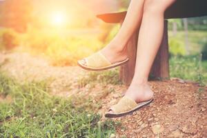 Legs of a beautiful woman sitting on a bench amidst flowers and nature, enjoying the fresh breeze in the morning . photo