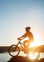 silueta de un hombre en bicicleta de montaña durante la puesta de sol. foto