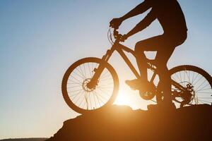 silueta de un hombre en bicicleta de montaña durante la puesta de sol. foto