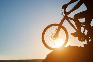 silueta de un hombre en bicicleta de montaña durante la puesta de sol. foto