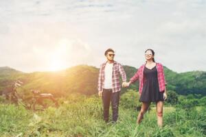 Young hipster couple holding hands walking on the meadow relaxing and natural atmosphere is very natural. photo