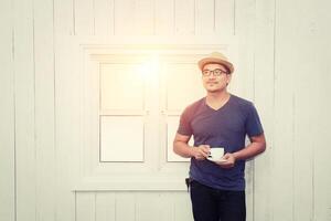 handsome young man with cup of coffee, enjoying life in front of  windows photo