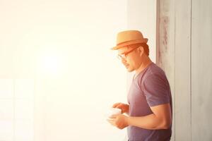 handsome young man with cup of coffee, enjoying life on outside balcony photo