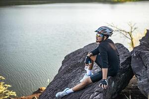 los ciclistas de montaña se sientan en la cima de la montaña y llevan una botella de agua foto