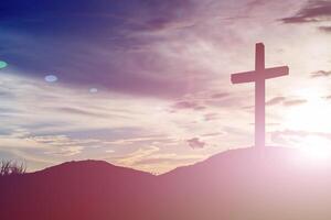 cross silhouette on the mountain at sunset photo