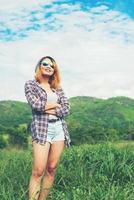 joven hermosa mujer hipster de pie con los brazos cruzados en medio de la naturaleza y la montaña, concepto relajante foto