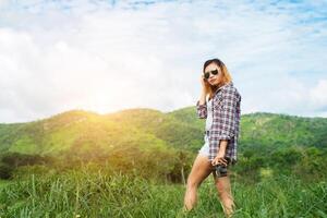 mujer joven hipster con cámara retro tomando un paisaje al aire libre, naturaleza de montaña de estilo de vida en el fondo. foto