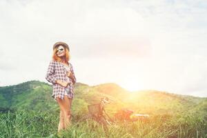 Beautiful hipster woman standing on a green meadow with nature and mountain background,Relaxing concept. photo