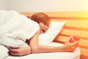 beautiful young woman shocked looking at alarm clock in the morning photo