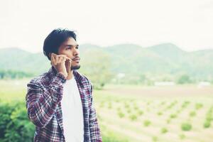 Young hipster bearded man talking on phone, smiling, outside mountain view. photo