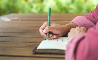 woman writing goal on notebook  at coffee shop outdoor space