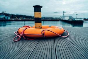 orange lifebuoy on the pier in the port in the evening photo